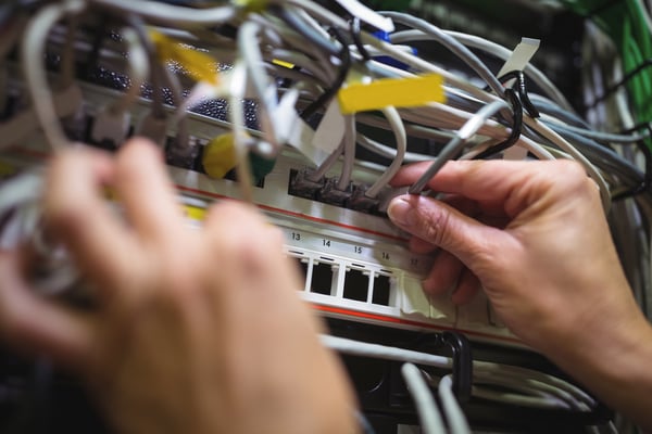 Technician plugging patch cable in a rack mounted server in server room-1